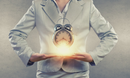 Close up of businesswoman holding in hands alarm clockの写真素材