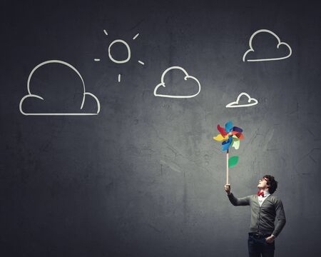 Young happy businessman with colorful windmill in handの写真素材