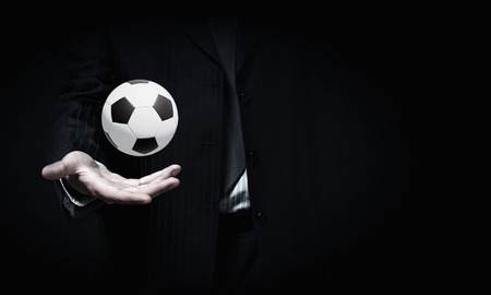 Close up of elegant businessman holding soccer ball in handの写真素材