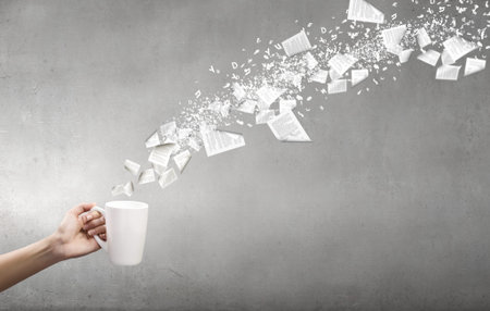 Hand holding coffee cup with flying out papersの写真素材