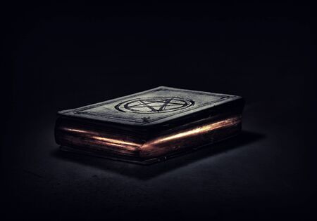 Old black magic book with lights on pagesの写真素材