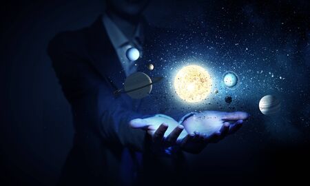 Young businesswoman holding in palm planet of sun systemの写真素材