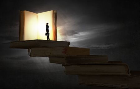 Big old opened book and miniature of businesswomanの写真素材