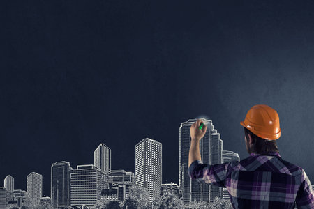 Back view of businessman drawing sketches of construction project on wall