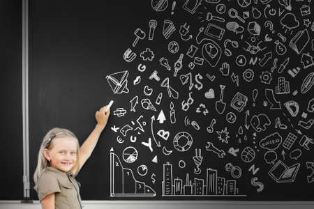 School girl writing graphs on blackboard with chalkの写真素材