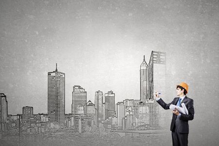 Young man engineer in helmet drawing construction projectの写真素材