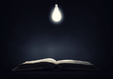 Old opened book and lamp hanging aboveの写真素材