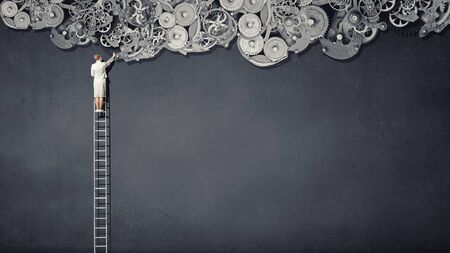 Rear view of businesswoman standing on top of ladderの写真素材