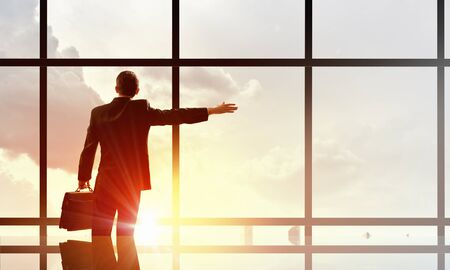 Businessman standing with back and looking in office windowの写真素材