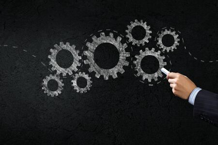 Close up of hand drawing gears mechanism with chalkの写真素材