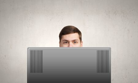 Young man looking out above laptop monitorの写真素材