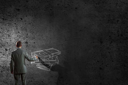 Back view of businessman drawing money banknotes on wallの写真素材