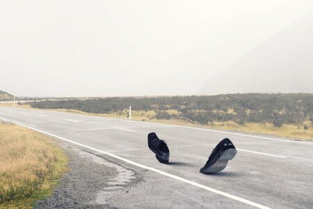 Pair of black shoes walking on roadの写真素材