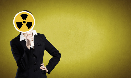 Unrecognizable businesswoman hiding her face behind radioactivity signの写真素材
