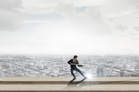 Concept of competition with businessman climbing office building with ropeの写真素材