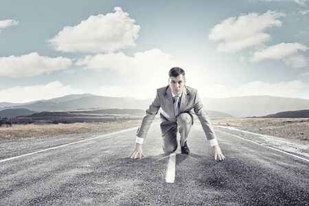 Young determined businessman standing in start positionの写真素材