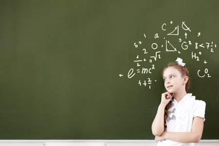 Pretty girl of school age standing at blackboard