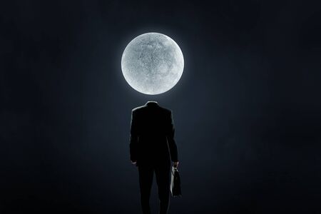 Faceless businessman with moon planet instead of headの写真素材
