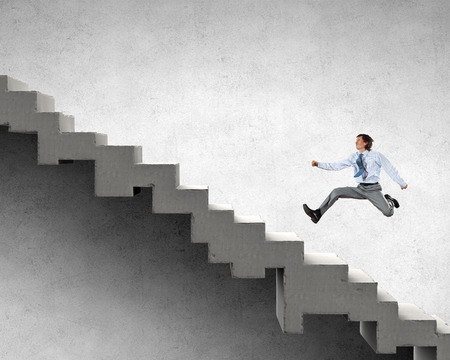 Young businessman walking up on staircase representing success conceptの写真素材
