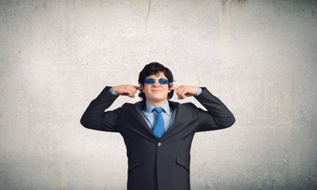 Annoyed businessman covering his ears with his handsの写真素材