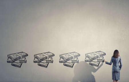 Back view of businesswoman drawing money banknotes on wallの写真素材