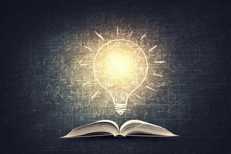 Old opened book with business sketches over black backgroundの写真素材