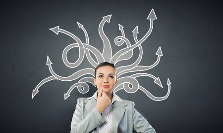 Young pensive businesswoman and thoughts coming out of her headの写真素材