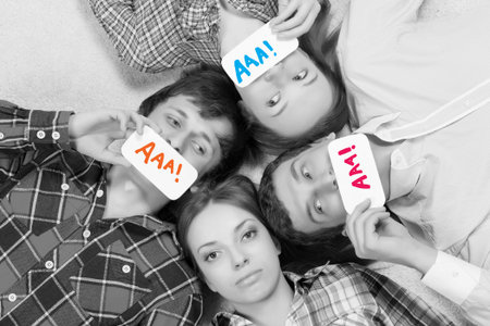 Group of young smiling people lying on floor in circle with phone symbols