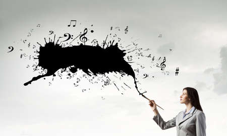 Young pretty businesswoman holding paint brush. Creativity conceptの写真素材