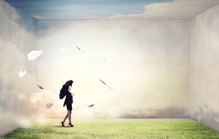 Bad luck and crisis concept with young businesswoman with black umbrellaの写真素材