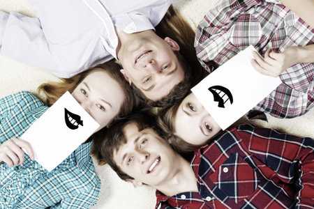 Group of young smiling people lying on floor in circle with phone symbols