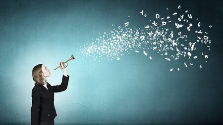 Young businesswoman in suit proclaiming something in hornの写真素材