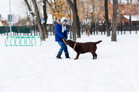 Kid of school age with dog in winter parkの写真素材