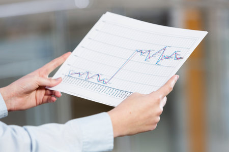 Close up of hands holding paper with graphs and diagrams