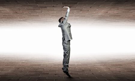 Businessman under pressure between two stone wallsの写真素材