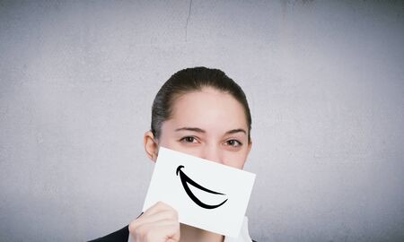 Pretty young girl holding white card with drawn smileの写真素材