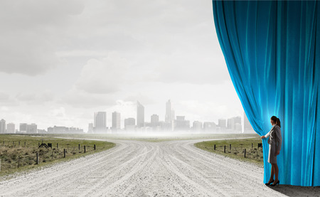 Businesswoman opening curtain to new roads and opportunitiesの写真素材