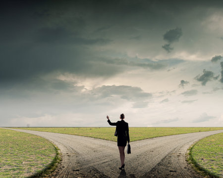 Back view of businesswoman standing on crossroads and making choiceの写真素材
