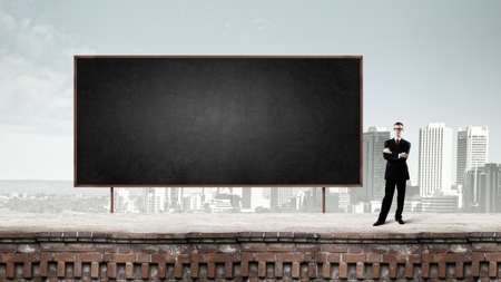 Young businessman in glasses and blank blackboardの写真素材