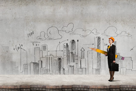 Young female engineer in hard hat with big pencil