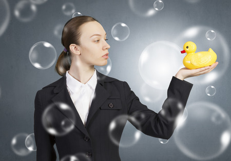 Young businesswoman holding yellow rubber duck toy in palmの写真素材