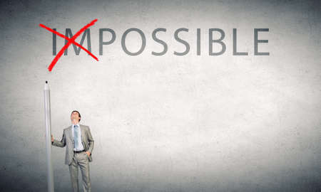 Young businessman with huge pencil changing word impossibleの写真素材