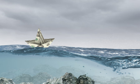Ship made of dollar banknote floating in waterの写真素材