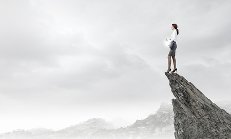 Cheerful businesswoman standing on rock edge and playing electric guitarの写真素材