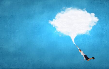 Young determined businesswoman flying high in sky on cloudの写真素材