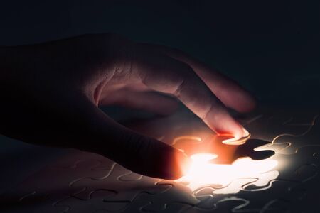 Hand connecting missing jigsaw glowing puzzle pieceの写真素材