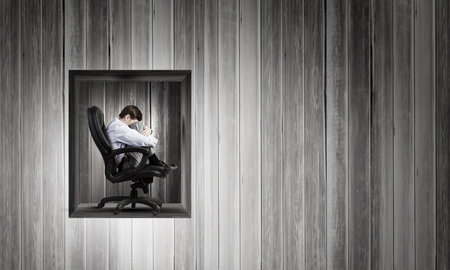 Young depressed businessman sitting in chair isolated from world