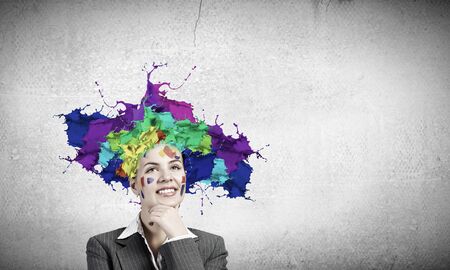 Thoughtful businesswoman with colorful splashes out of his headの写真素材