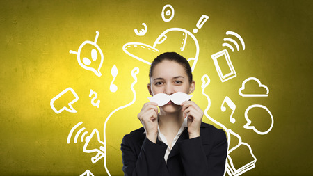 Happy cute girl trying male paper mustacheの写真素材