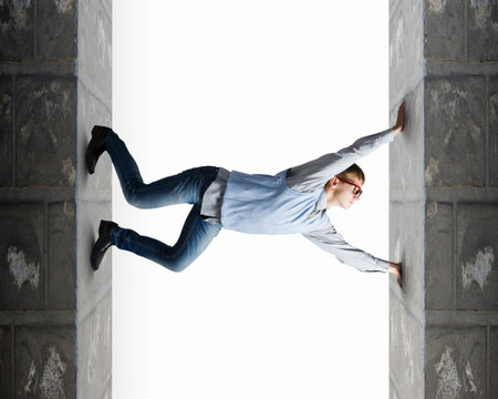 Young man under pressure between two stone walls